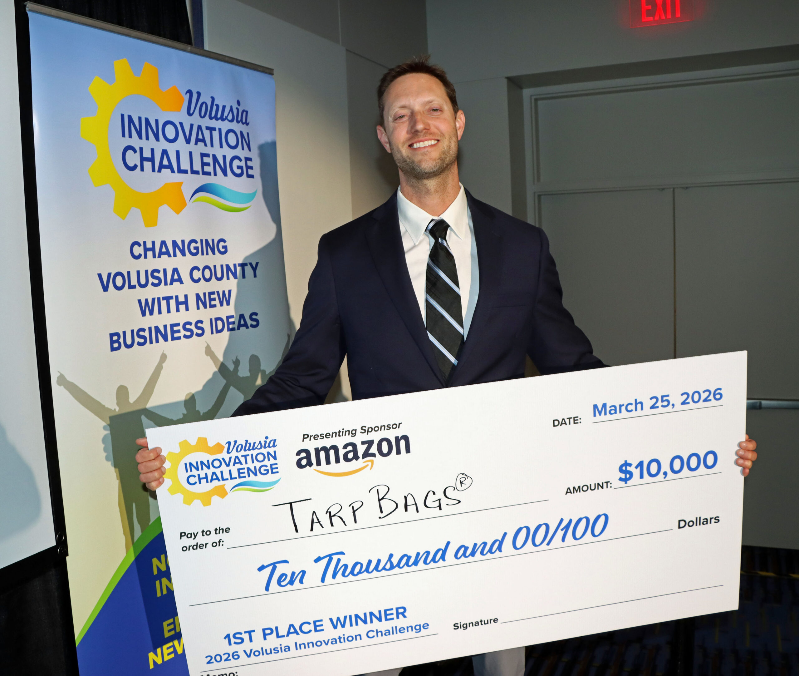 Steve Lofvers, 1st place winner of the 2026 Volusia Innovation Challenge holding his $10,000 big check on the stage.